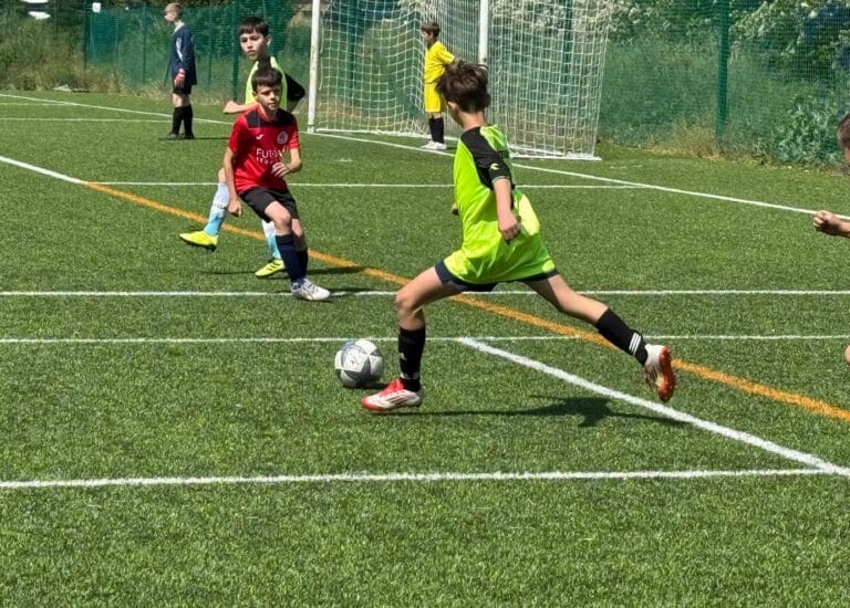 Deti hrajú futbal na ihrisku s umelou trávou